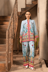 Woman wearing a colorful traditional outfit standing in a rustic setting with wooden stairs.