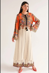 Woman wearing a colorful top and beige pants with black patterns on a white background