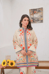 Woman wearing a cream dress with colorful patterns in a room setting.
