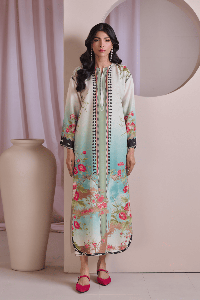 Woman wearing a floral dress with a decorative border in a minimalistic setting.