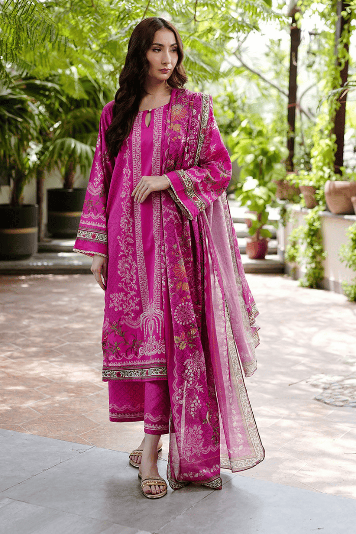 Woman wearing a pink traditional outfit with intricate patterns in an outdoor setting.