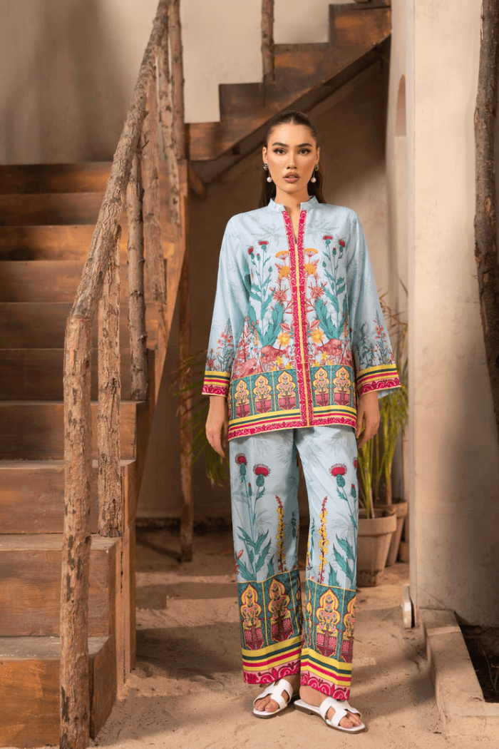 Woman wearing a colorful traditional outfit standing in a rustic setting with wooden stairs.