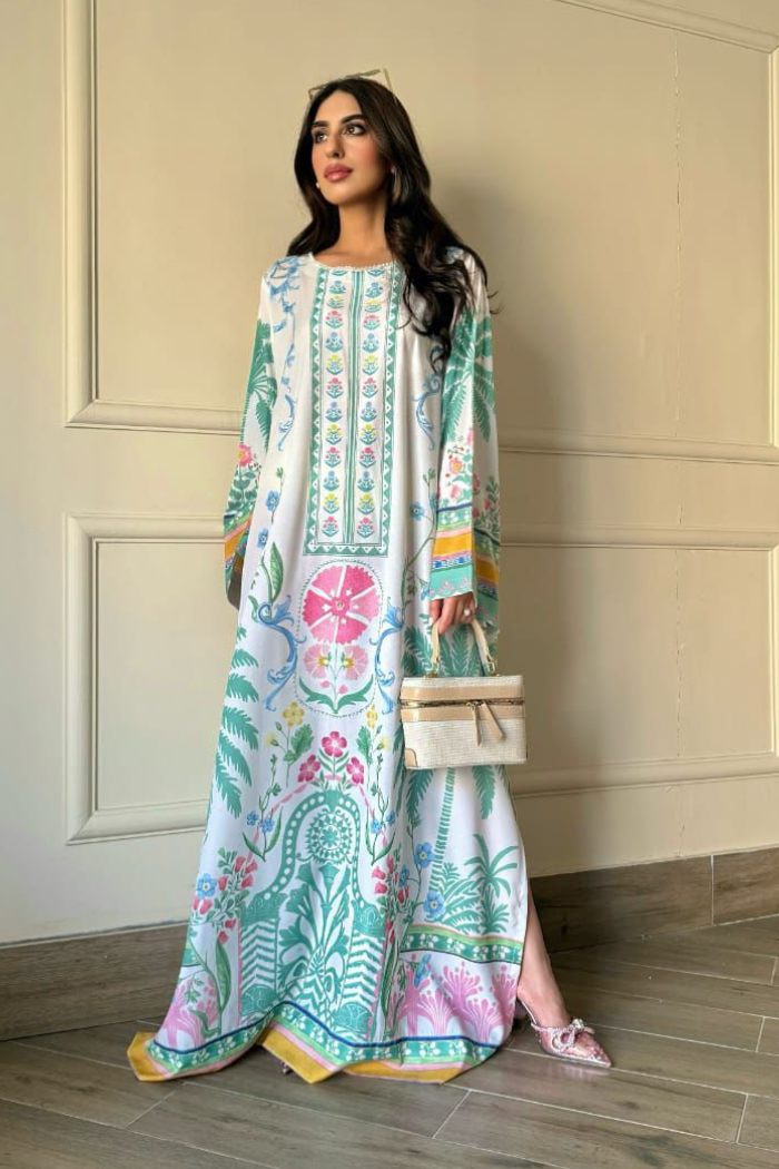Woman wearing a colorful floral dress against a beige wall.