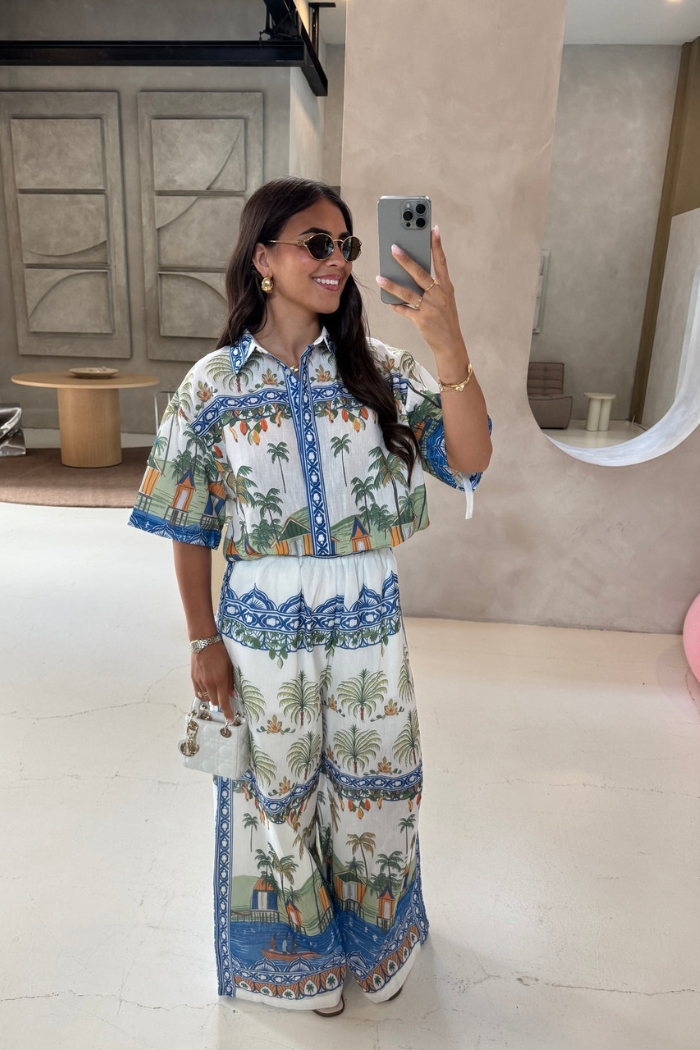 Woman taking a mirror selfie wearing a colorful outfit with palm tree patterns.