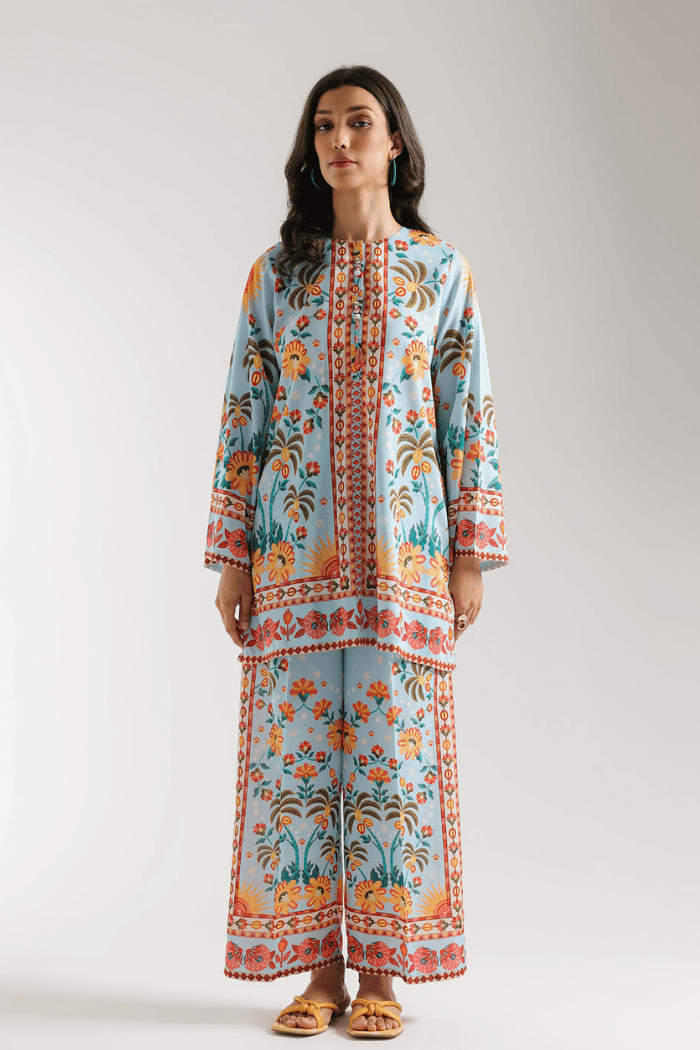 Woman wearing a long, patterned dress against a plain background