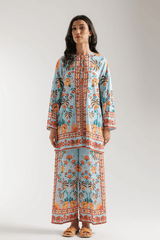 Woman wearing a long, patterned dress against a plain background