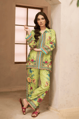 Woman wearing a green embroidered traditional outfit in a room with a window.