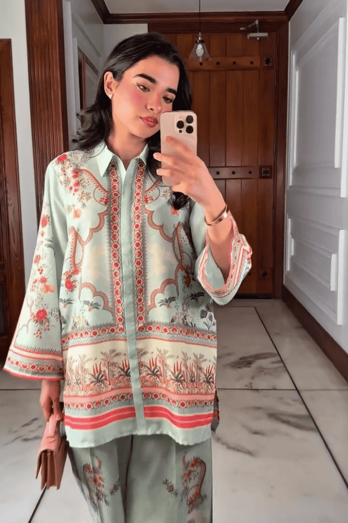 Woman taking a mirror selfie wearing a patterned outfit in a home setting.