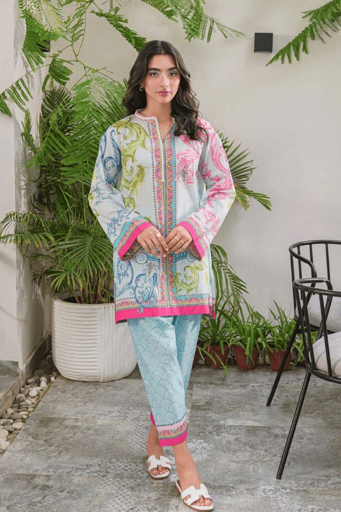 Woman wearing a colorful traditional outfit with a white background and plants.