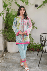 Woman wearing a colorful traditional outfit with a white background and plants.