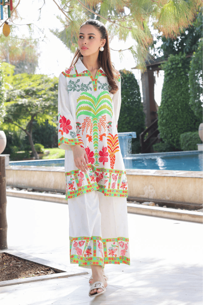 Woman wearing a colorful  dress with a pool and garden in the background