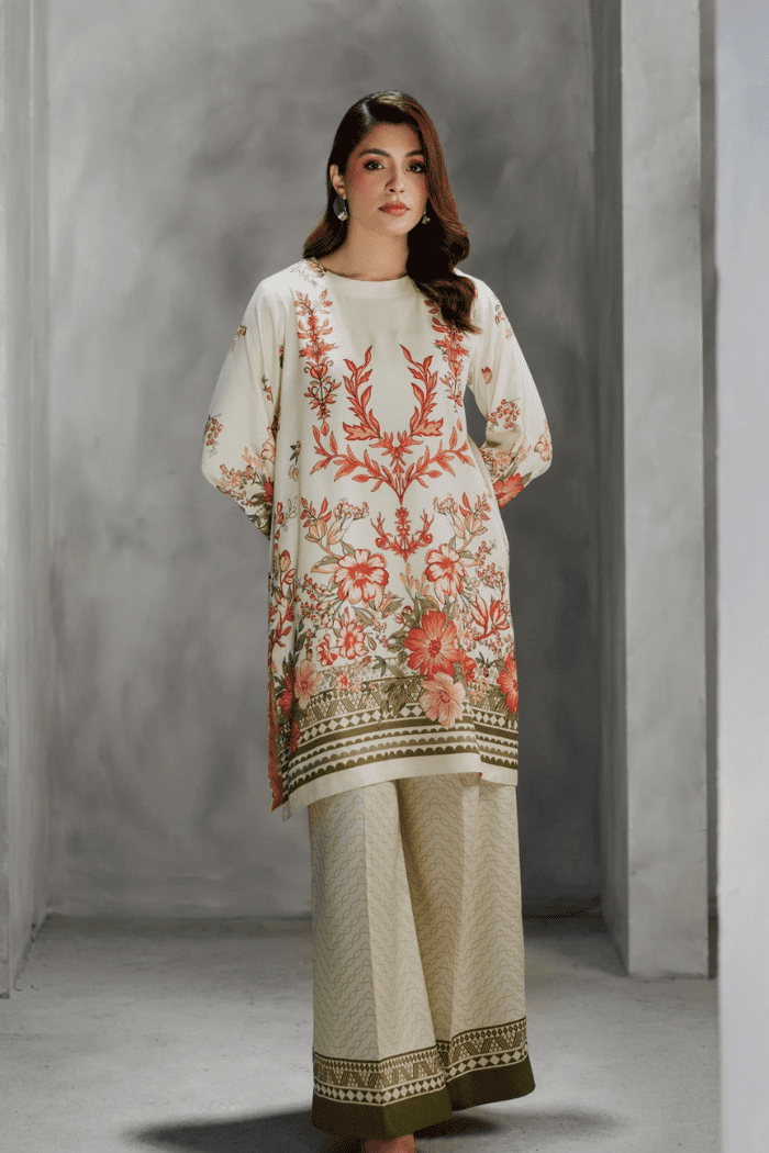 Woman wearing a cream embroidered outfit against a gray background