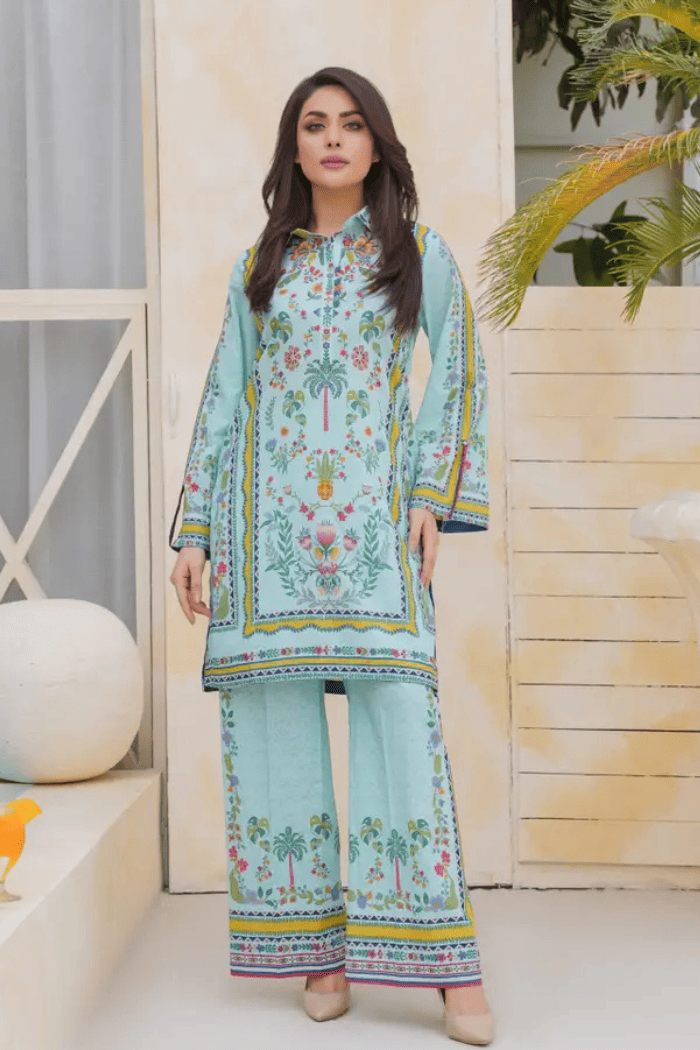 Woman wearing a light blue  outfit with colorful patterns in an indoor setting.