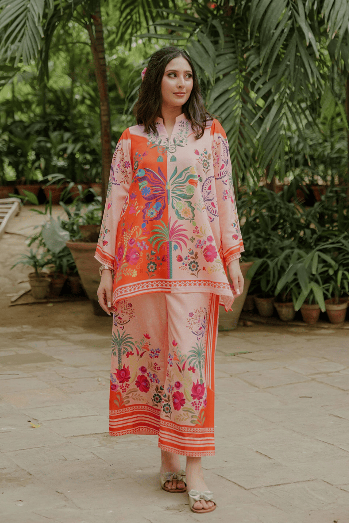 Woman wearing a colorful outfit in an outdoor setting with plants.