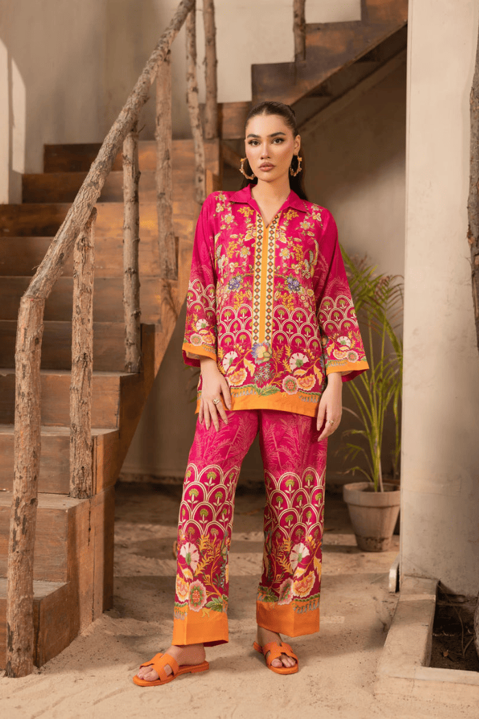 Woman in a vibrant traditional outfit standing in a home setting with wooden stairs.
