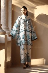 Woman wearing a patterned outfit standing in a sunlit room with columns.