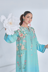 Woman wearing a light blue floral embroidered dress holding a white flower against a gray background