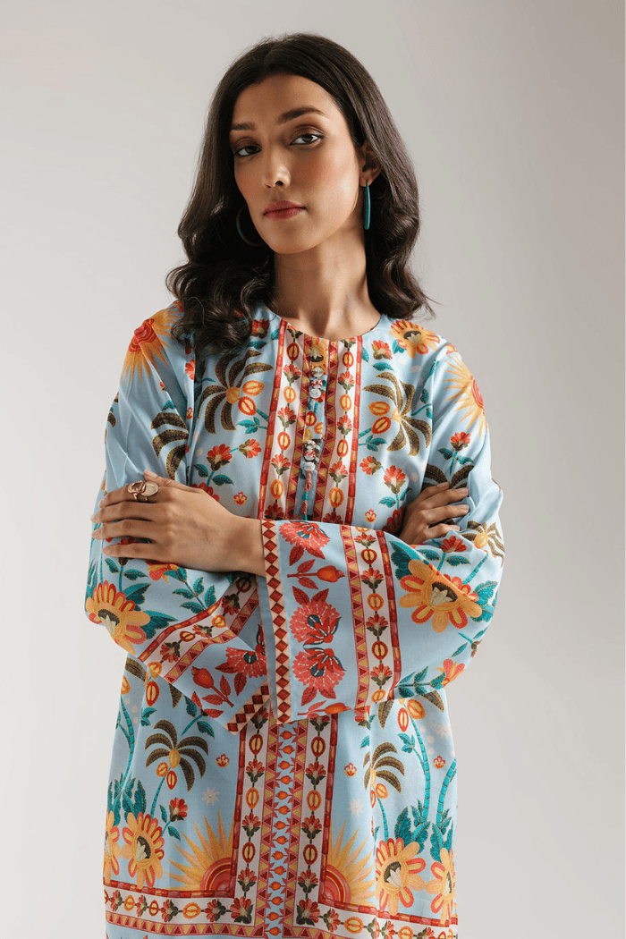 Woman wearing a colorful floral and geometric patterned top against a plain background