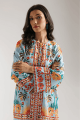 Woman wearing a colorful floral and geometric patterned top against a plain background
