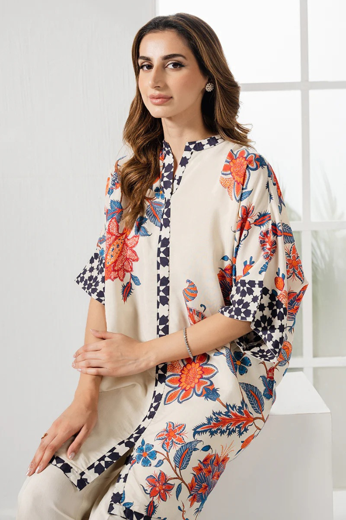 Woman wearing a floral kimono-style garment in a bright room.