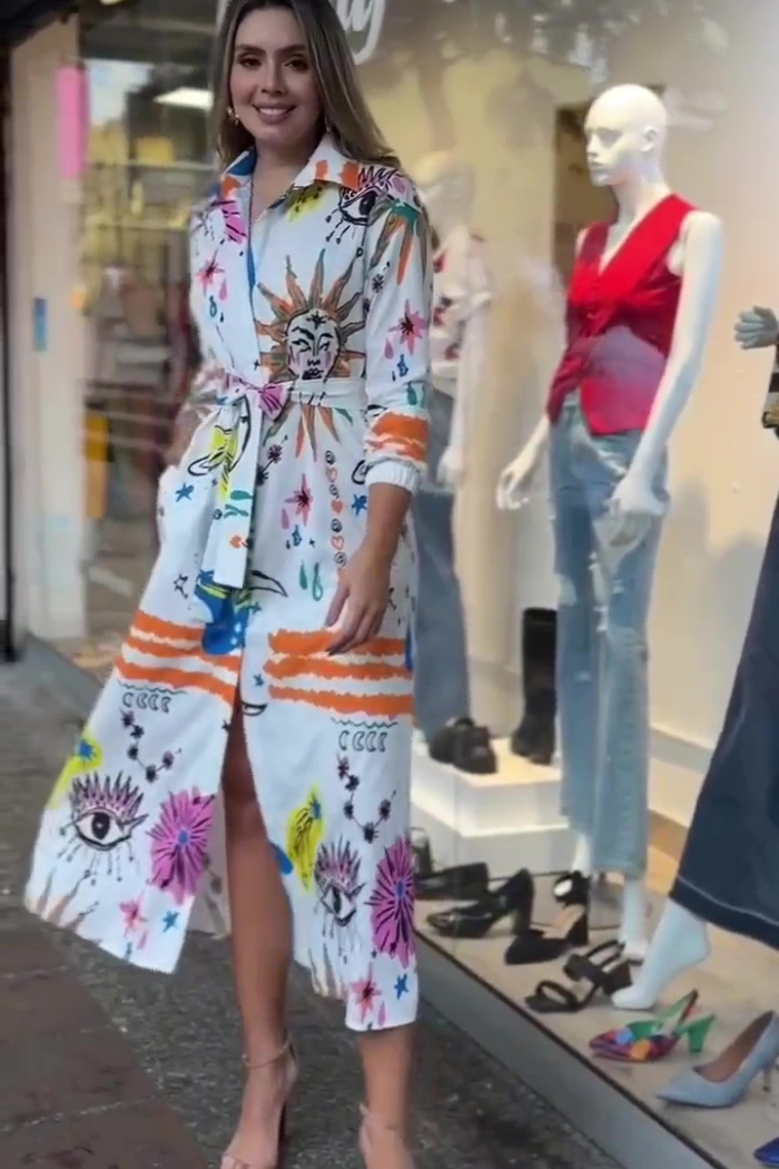Woman wearing a colorful dress standing in front of a store window display.