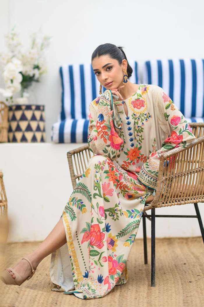 Woman in a floral dress sitting on a chair in a room with a blue and white striped curtain.