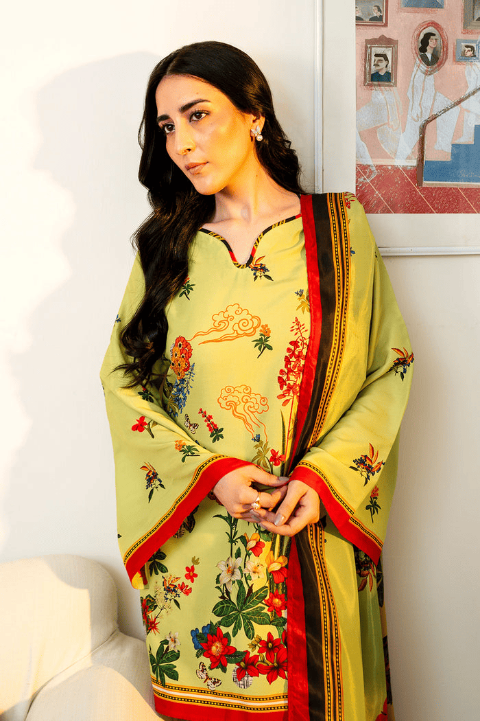 Woman wearing a traditional yellow saree with floral patterns indoors.