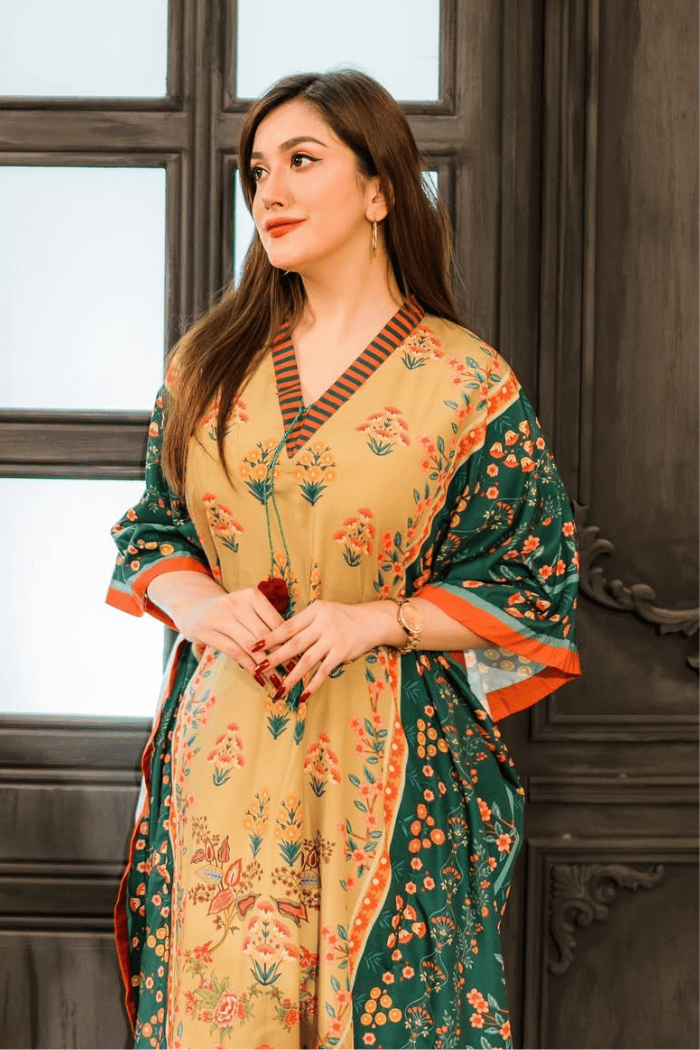 Woman wearing a floral dress with a green and orange border in an indoor setting.
