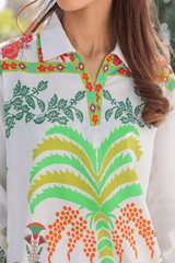 Woman wearing a colorful patterned shirt with green, orange, and red design.