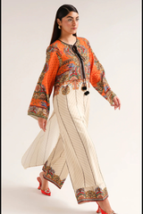 Woman wearing a traditional outfit with an orange top and white pants on a plain background