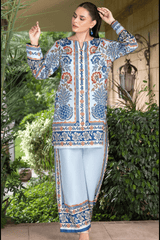 Woman wearing a patterned blue and white outfit with light blue pants, standing outdoors.