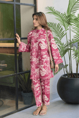 Woman in a pink floral outfit standing indoors with plants in the background