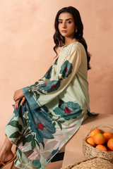 Woman wearing a floral dress sitting on a peach-colored background with a basket of oranges.