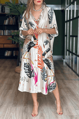 Woman wearing a patterned dress standing in a room with books and plants.