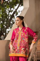 Woman wearing a vibrant pink traditional outfit with intricate patterns, standing outdoors.