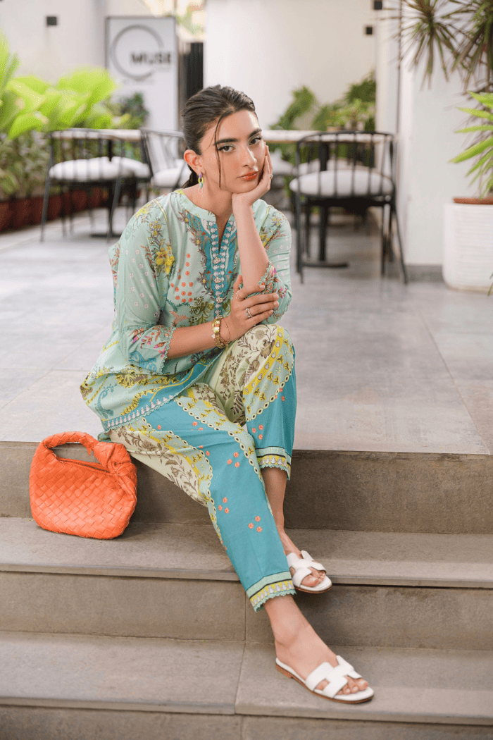 Woman in a floral outfit sitting on steps with an orange bag