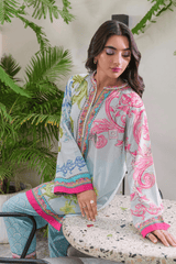 Woman wearing a light blue and pink embroidered outfit sitting on a chair with plants in the background