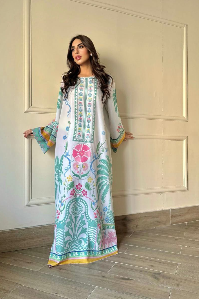 Woman wearing a floral dress standing against a white paneled wall.