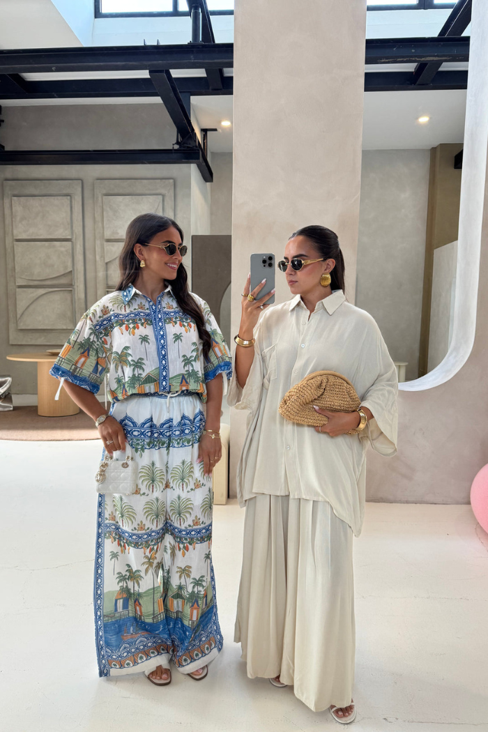 Two women taking a mirror selfie in a stylish setting.
