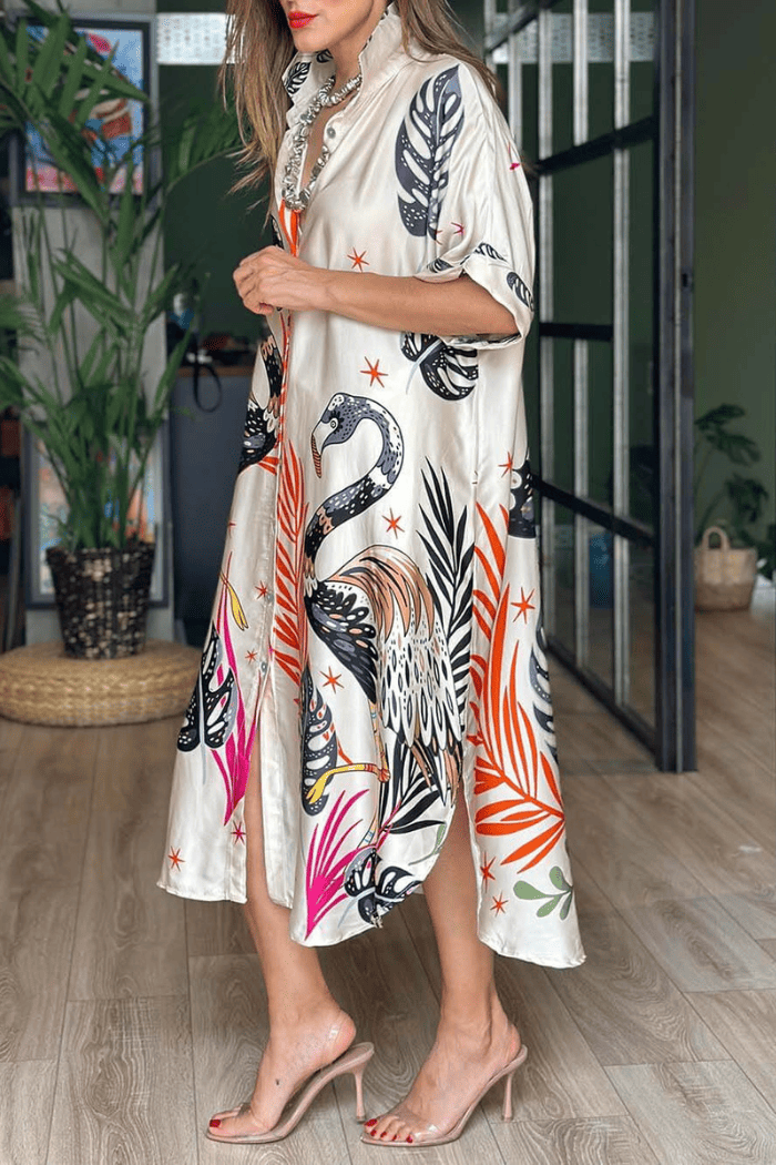 Woman wearing a stylish dress with colorful swan and leaf pattern indoors.