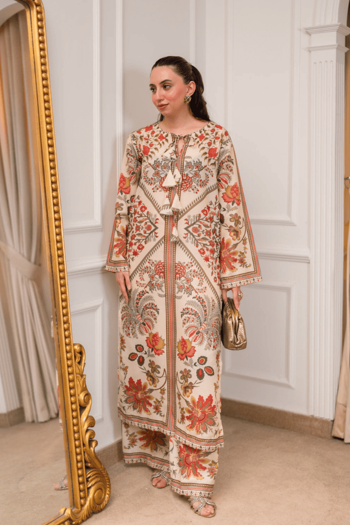 Woman in a floral dress standing next to a gold-framed mirror in an elegant room.