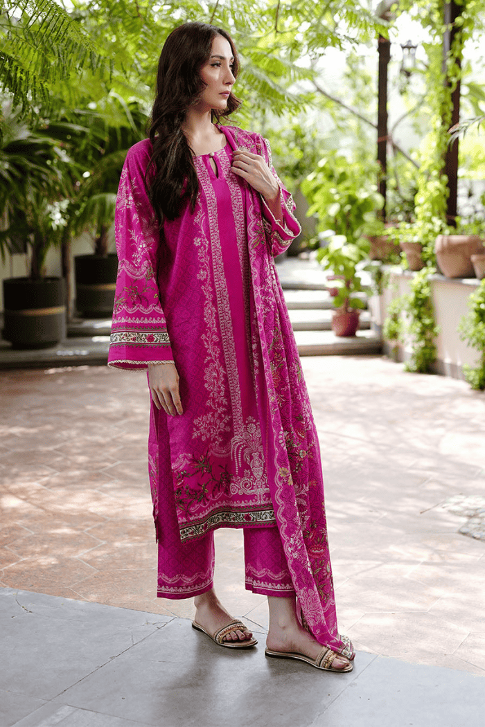 Woman wearing a pink traditional outfit with embroidery in an outdoor setting.