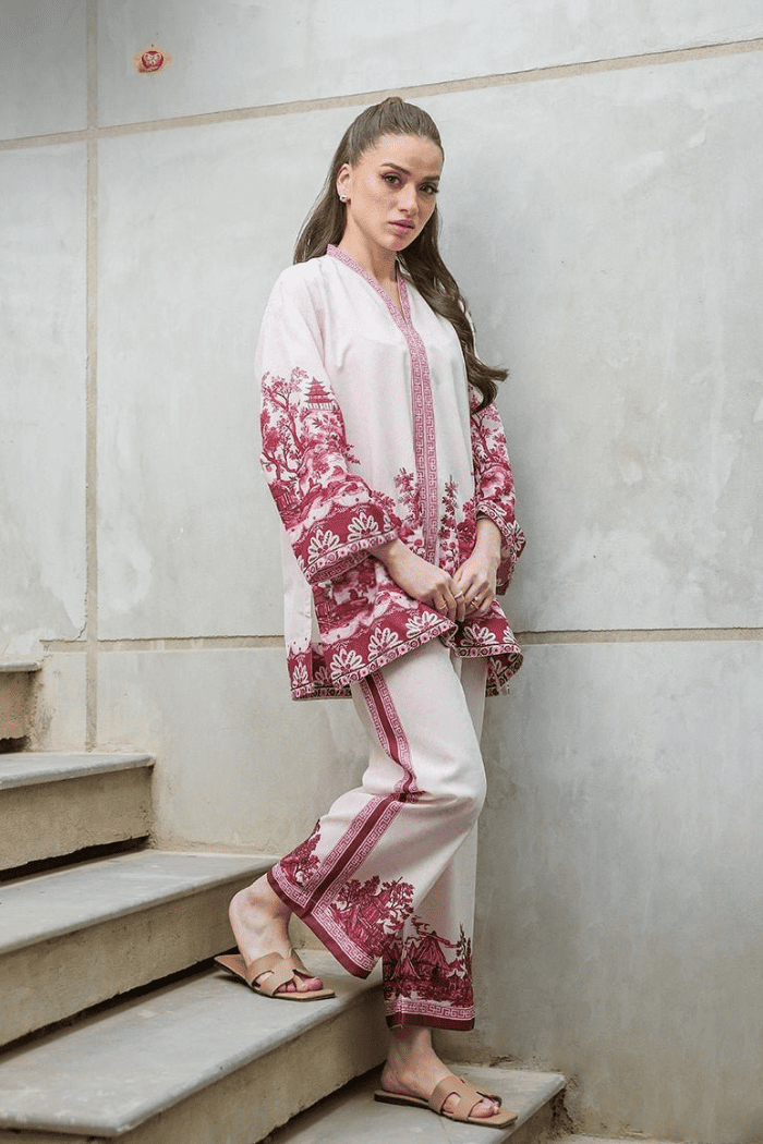 Woman in a traditional outfit with pink and white  standing on steps.