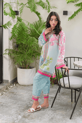Woman in a floral outfit standing outdoors with plants and furniture in the background