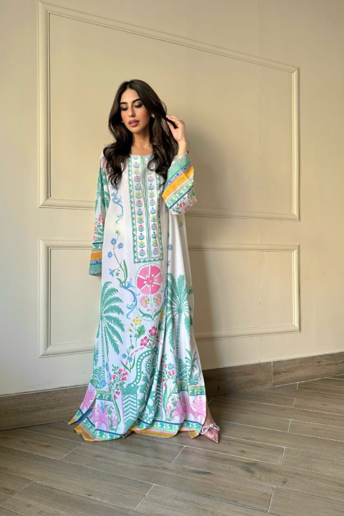 Woman wearing a colorful floral dress in a room with wooden flooring and white walls.