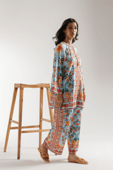 Woman wearing a floral outfit standing next to a wooden stool on a white background
