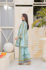 Woman in a light blue traditional outfit with floral patterns standing in a modern indoor setting.