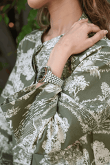 Person wearing a green patterned shirt with a close-up of a wrist wearing a silver watch.