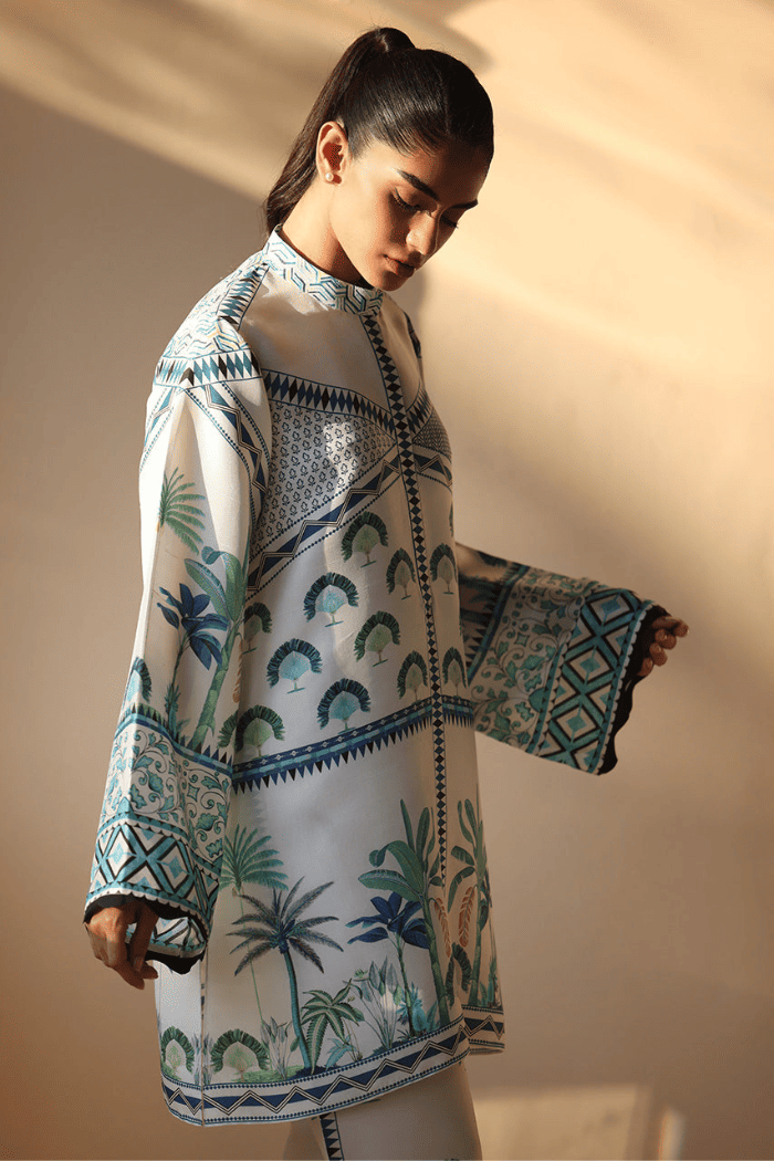 Woman wearing a patterned shirt with palm tree design against a plain background