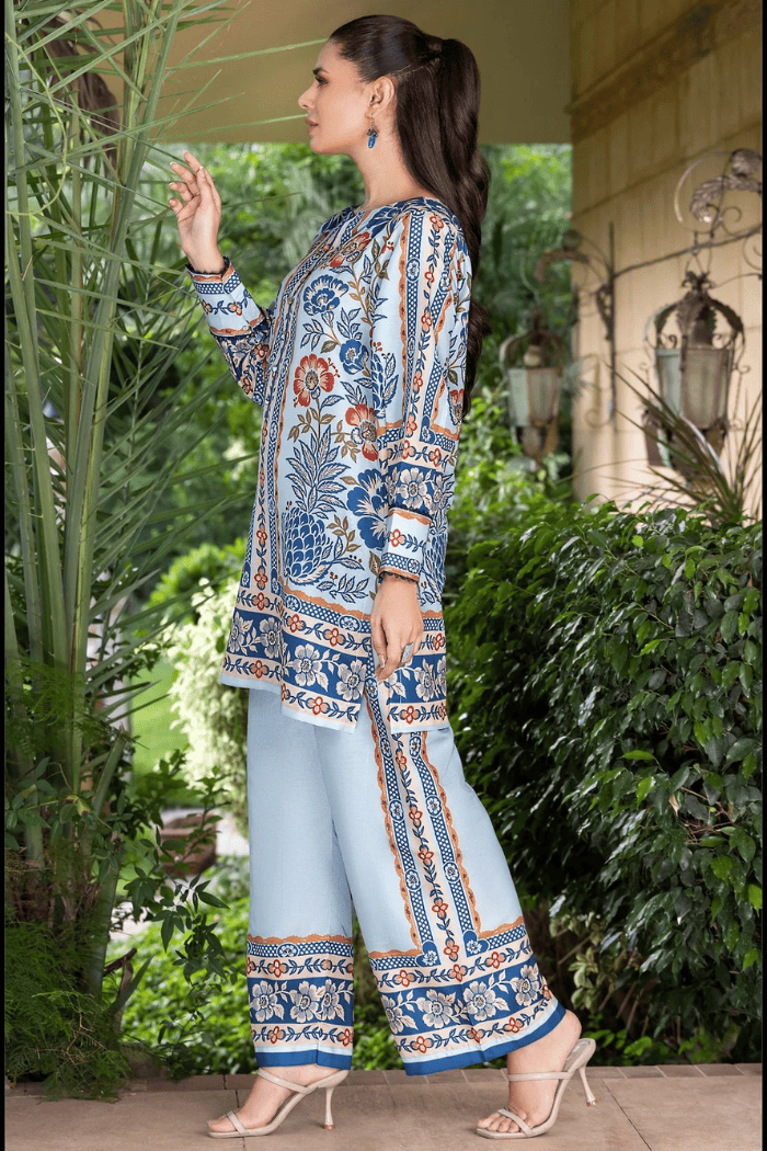 Woman wearing a patterned outfit standing outdoors with greenery in the background